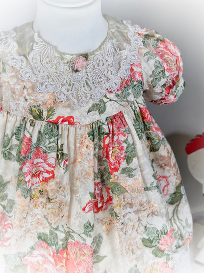 3 years. Cream vintage floral dress with puff sleeves, satin and lace bib and pink rosette