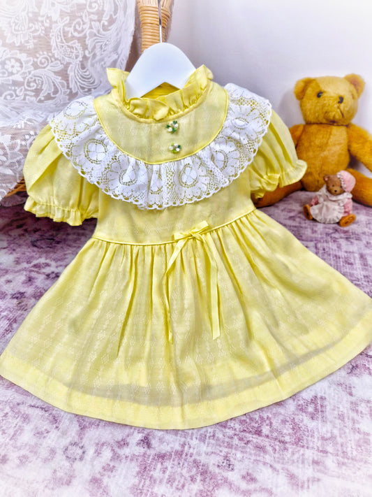 12-18 months. Lemon vintage dress by Toddle Time with white lace details across chest, ruffle neck and puff sleeves