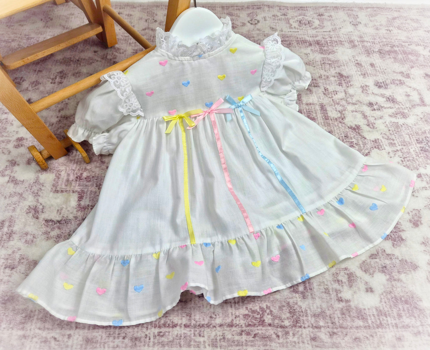 9-12 months. White vintage dress with pink, blue and lemon embroidered hearts and satin ribbons and bows