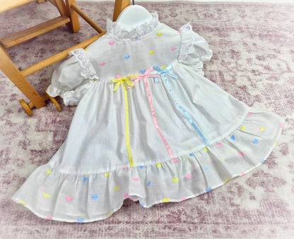 9-12 months. White vintage dress with pink, blue and lemon embroidered hearts and satin ribbons and bows