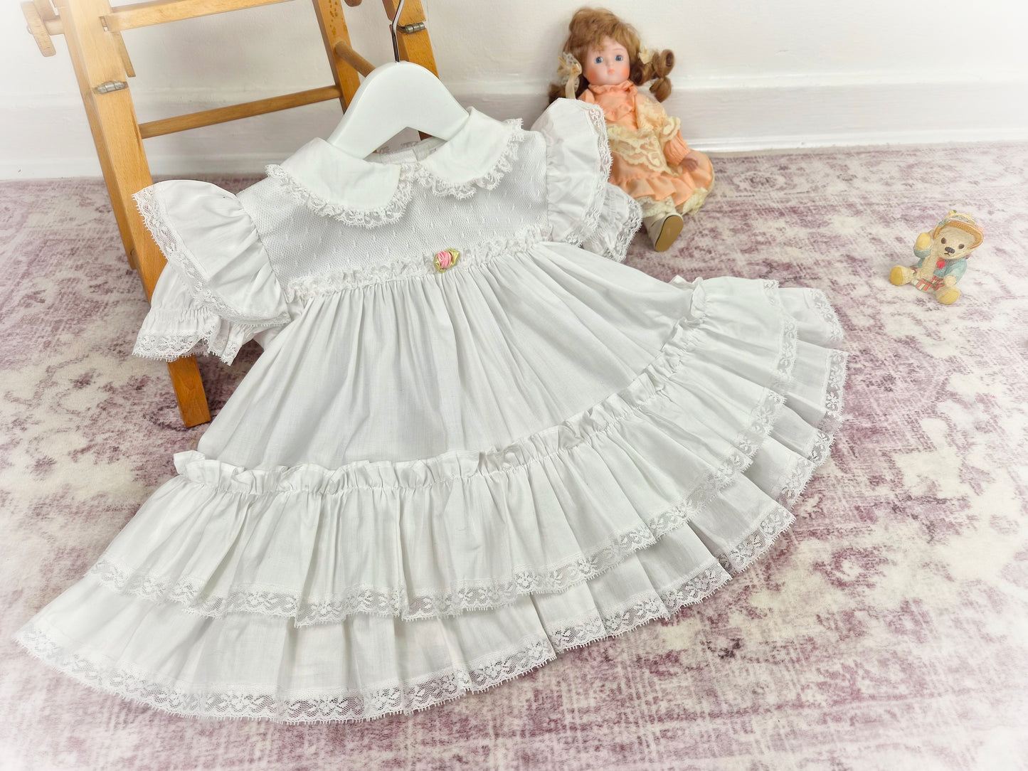 12-18 months. White frilly vintage dress by Bryan with lace and a pink rosette