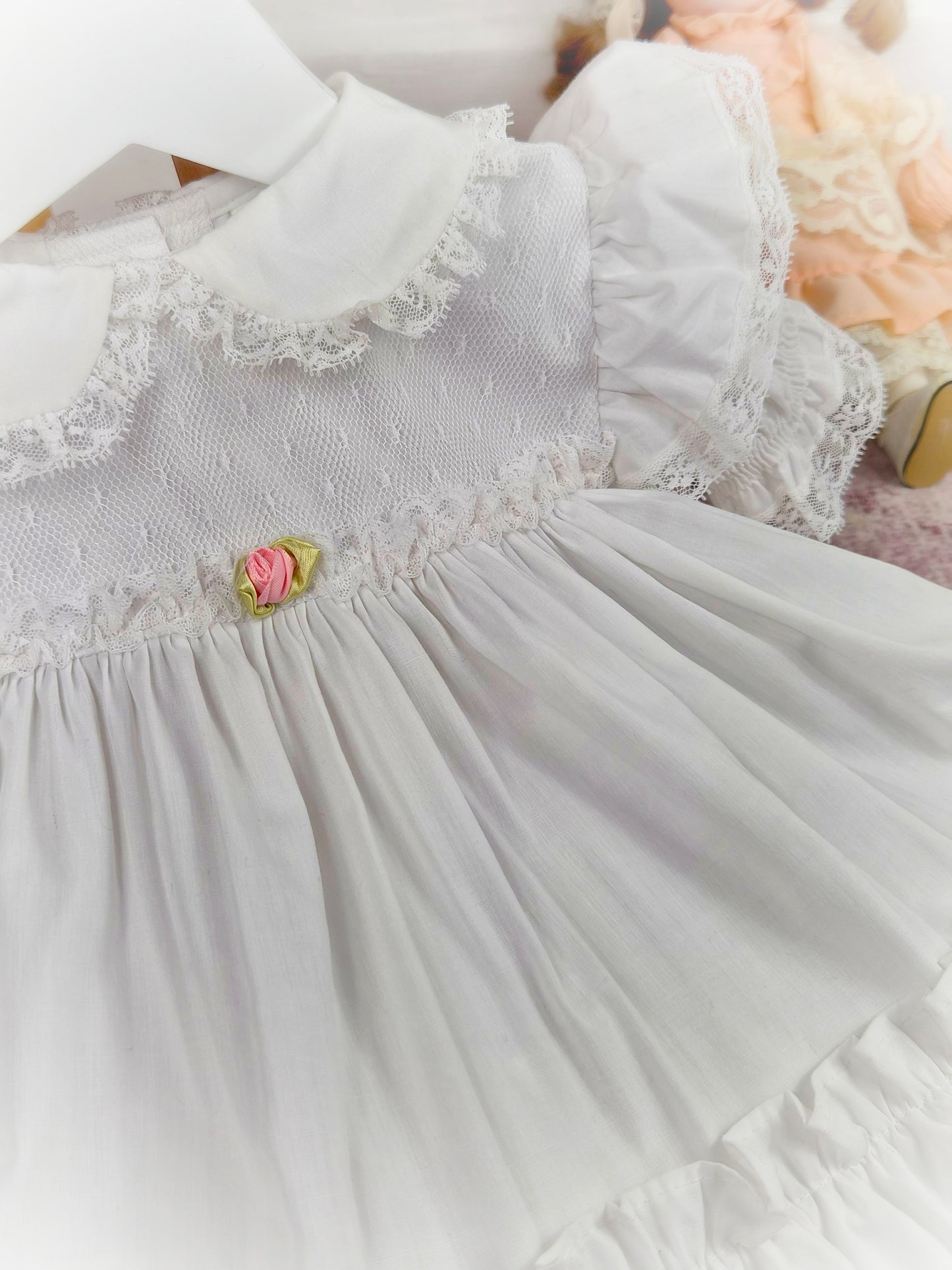 12-18 months. White frilly vintage dress by Bryan with lace and a pink rosette