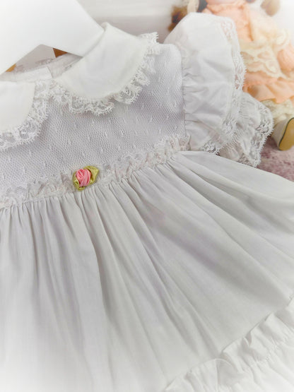 12-18 months. White frilly vintage dress by Bryan with lace and a pink rosette
