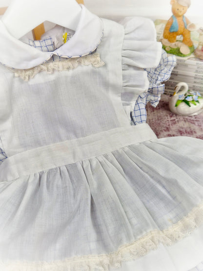 9-12 months. White and blue checked dress with white apron and frilly shoulders