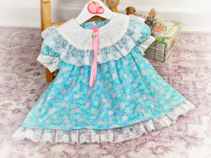 12 months. Turquoise vintage dress from Evy with pink floral print, white lace bib and hem and pink satin ribbon