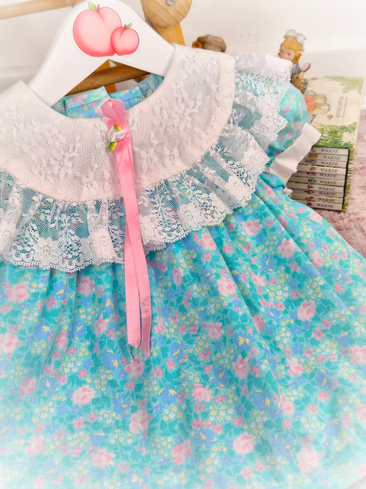 12 months. Turquoise vintage dress from Evy with pink floral print, white lace bib and hem and pink satin ribbon