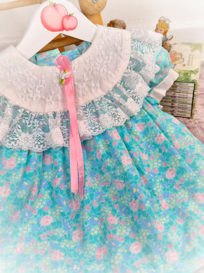 12 months. Turquoise vintage dress from Evy with pink floral print, white lace bib and hem and pink satin ribbon