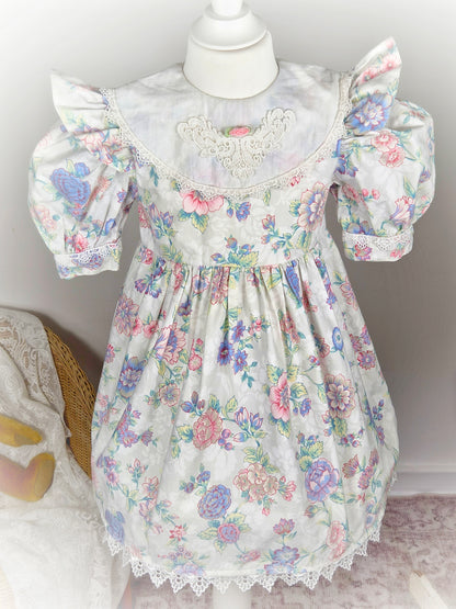 4-5 years. White vintage dress with floral design, puff sleeves, large bib and rosette