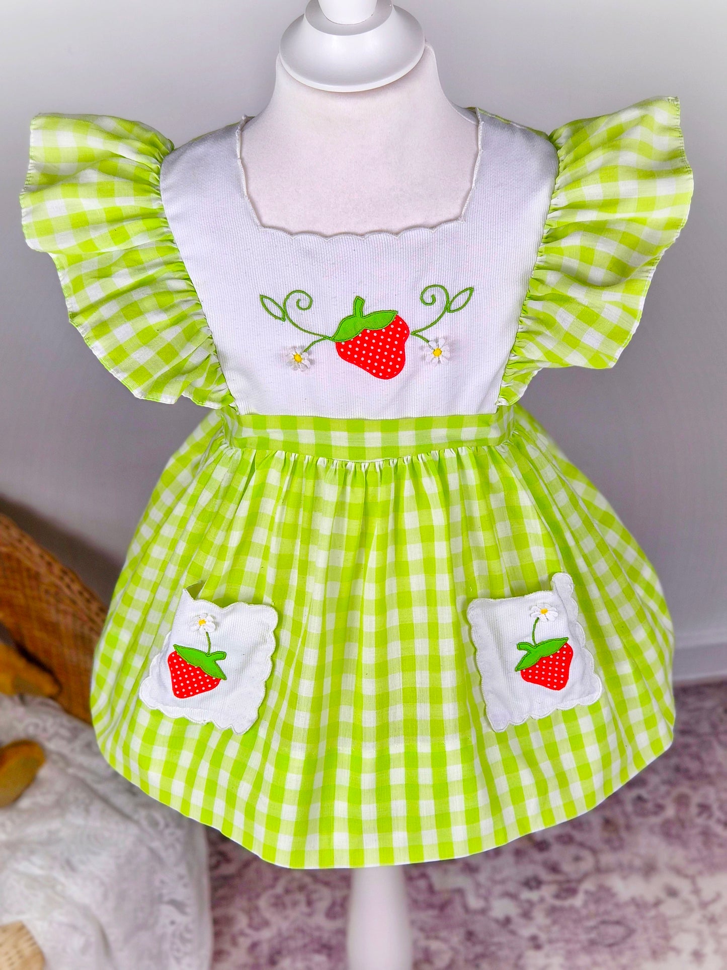 2-3 years. Green and white vintage gingham dress with flutter sleeves, white bib and pockets embroidered with strawberries from Nannette