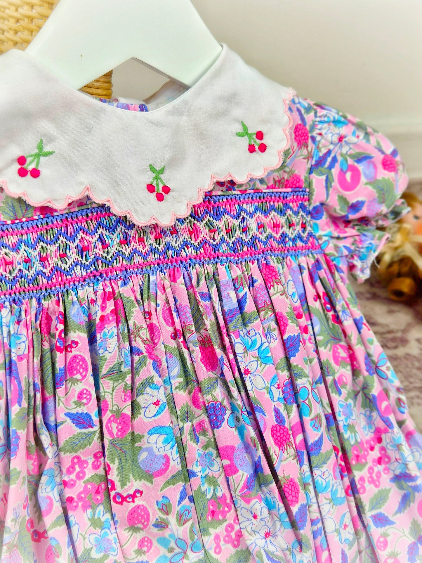 9-12 months. Bright vintage floral smocked romper with white collar and embroidered cherries