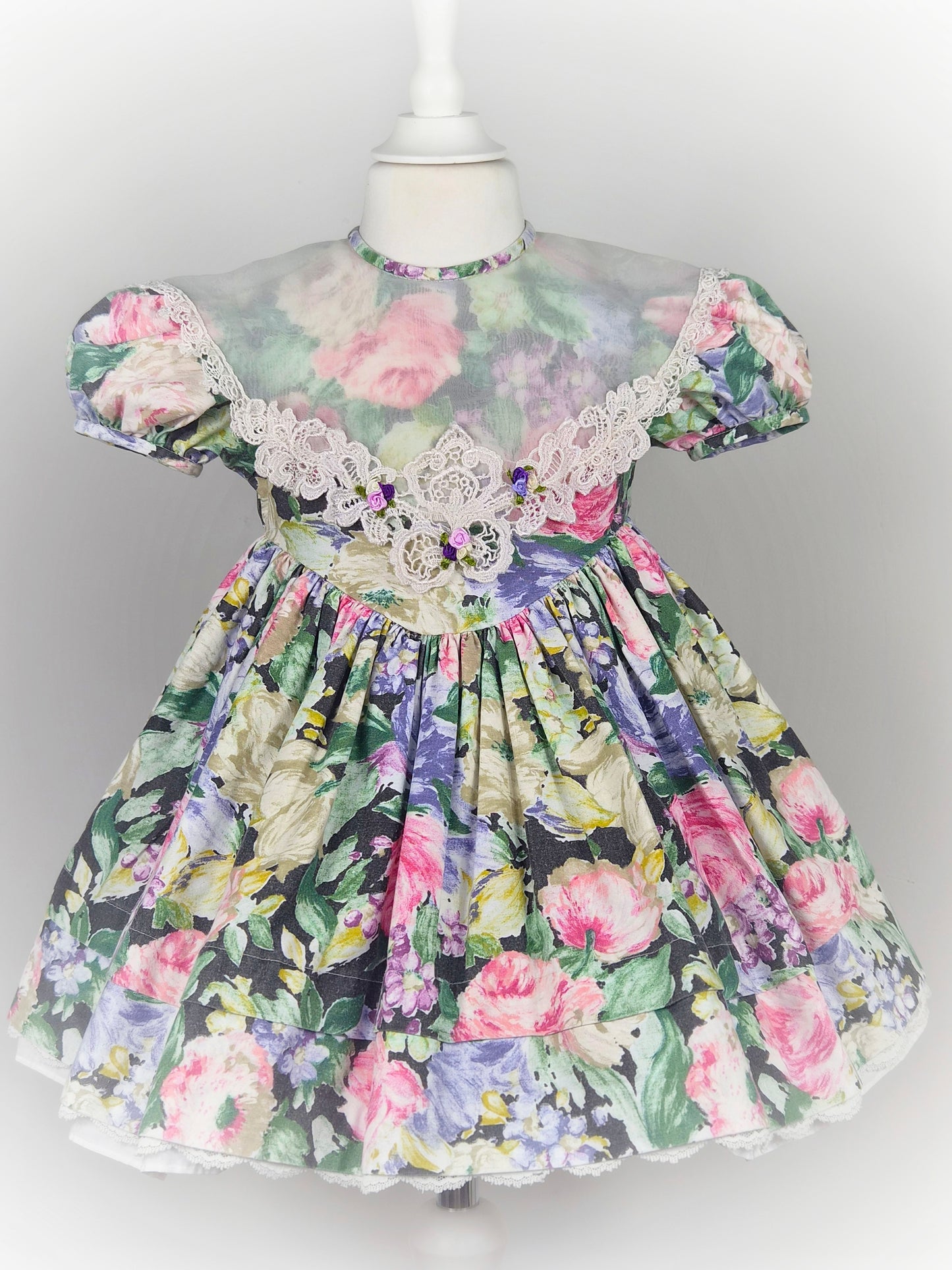3 years. Vintage floral dress with puff sleeves, large sheer bib trimmed with lace and rosettes
