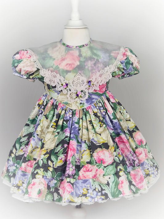 3 years. Vintage floral dress with puff sleeves, large sheer bib trimmed with lace and rosettes