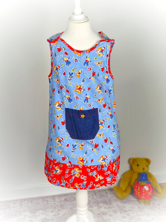 5-6 years. Blue and red handmade sleeveless dress with cowboys print, denim pocket and star button