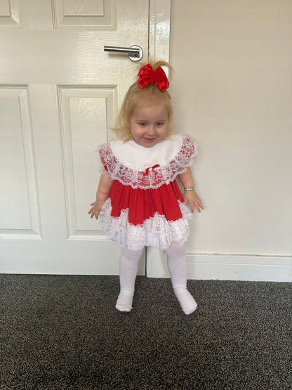 6-12 months. Red Lid'l Dolly with white bib and lace ruffles