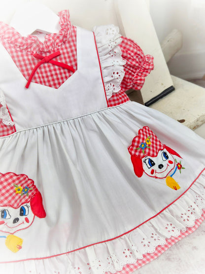 9-12 months. Red and white gingham dress with white mock apron, eyelet details and little sheep appliques