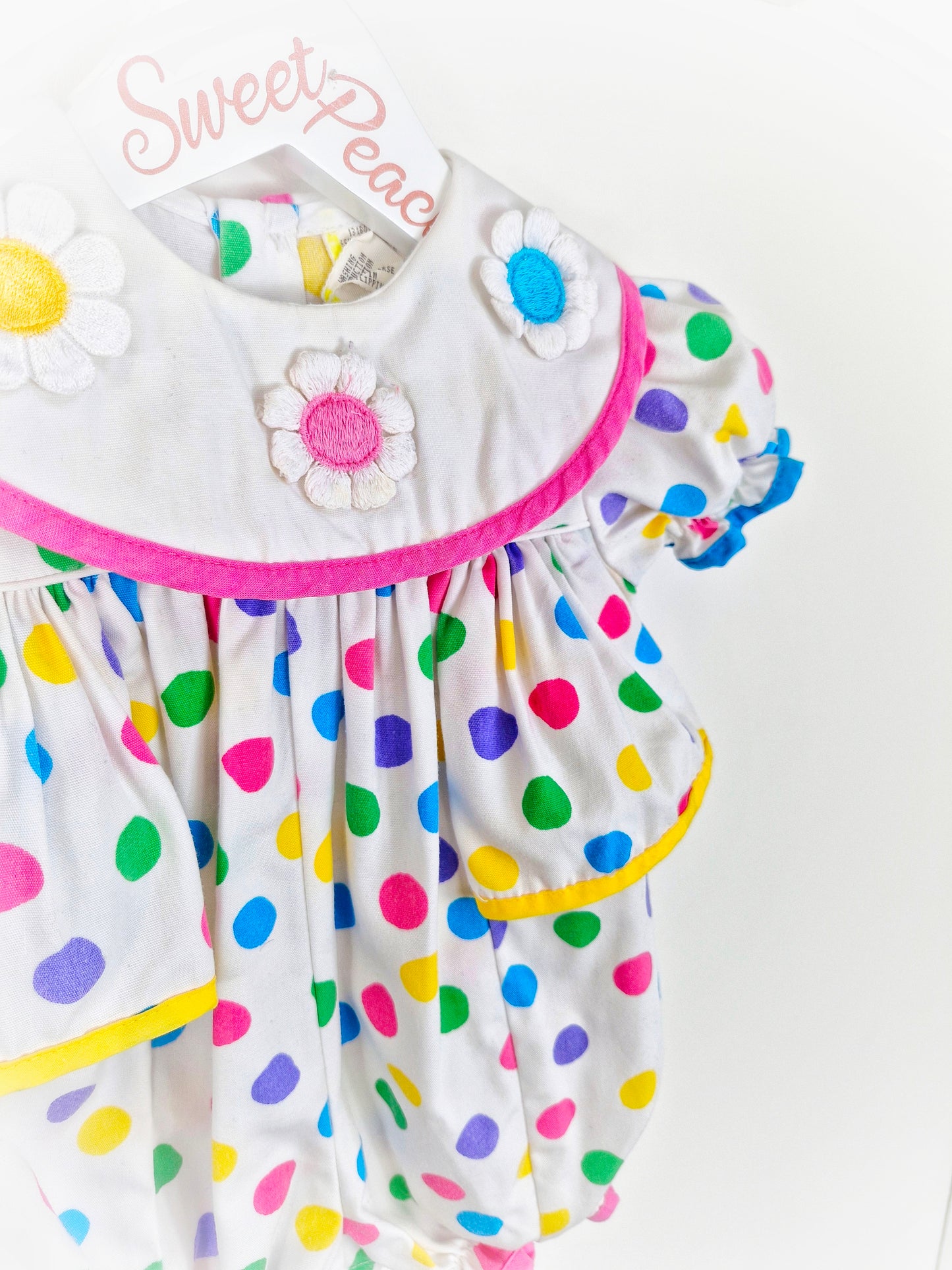9-12 months. White romper with bright coloured spots and flowered bib