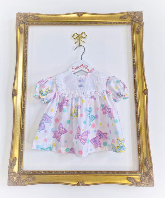 6-9 months. White 80s dress with bow print and buttons.