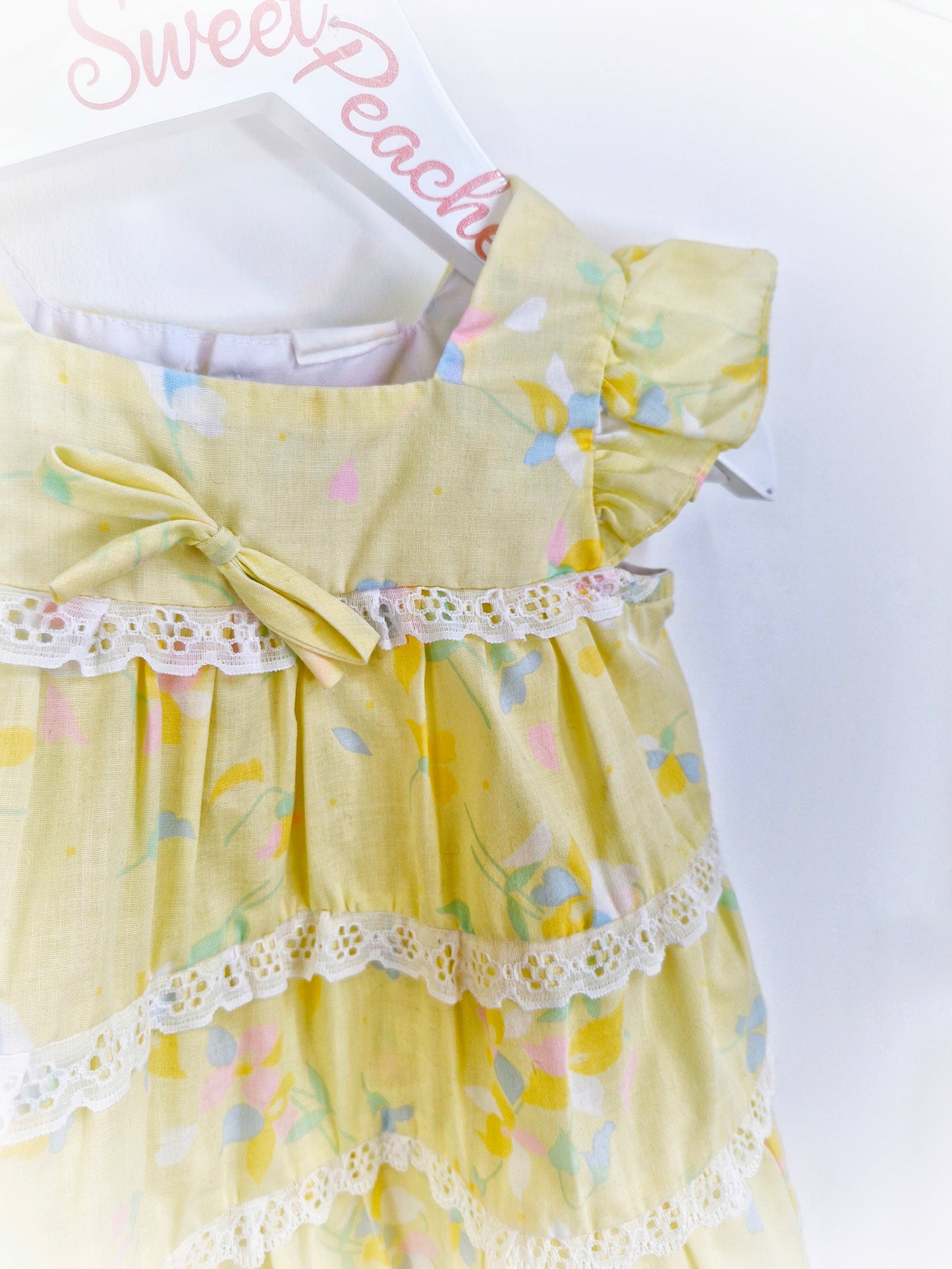 9-12 months. Lemon dress with flutter sleeves, floral print and lace details