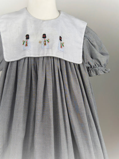 10 years. Black and white gingham, vintage handmade dress by Amanda Kertzembend with large white bib embroidered with snowmen