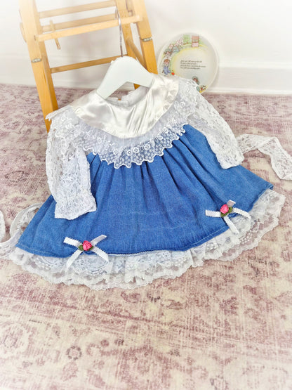 12-18 months. Vintage dress by Shanil, denim with white lace sleeves and hem, satin bib and pink rosettes