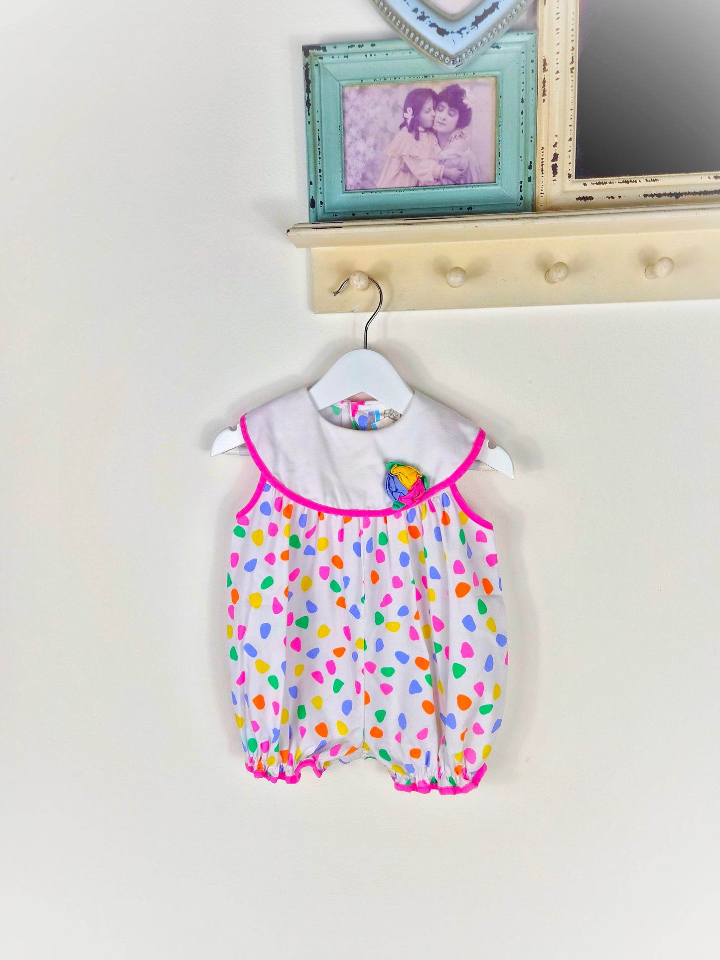 12 months. White vintage short, sleeveless romper with bright spots and flower on bib