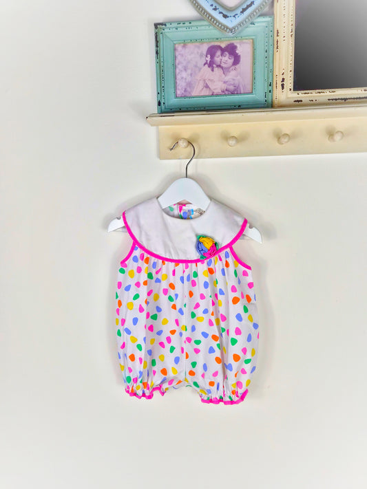 12 months. White vintage short, sleeveless romper with bright spots and flower on bib