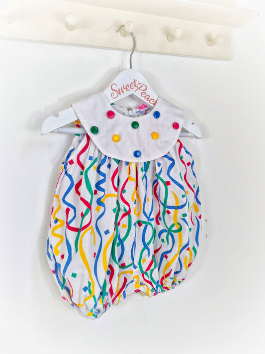 9 months. Polly Flinders romper with primary coloured buttons and print