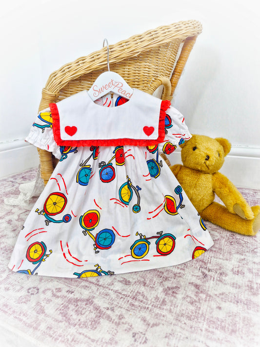 12-18 months. White handmade dress with red hearts and lace on bib and bicycle print