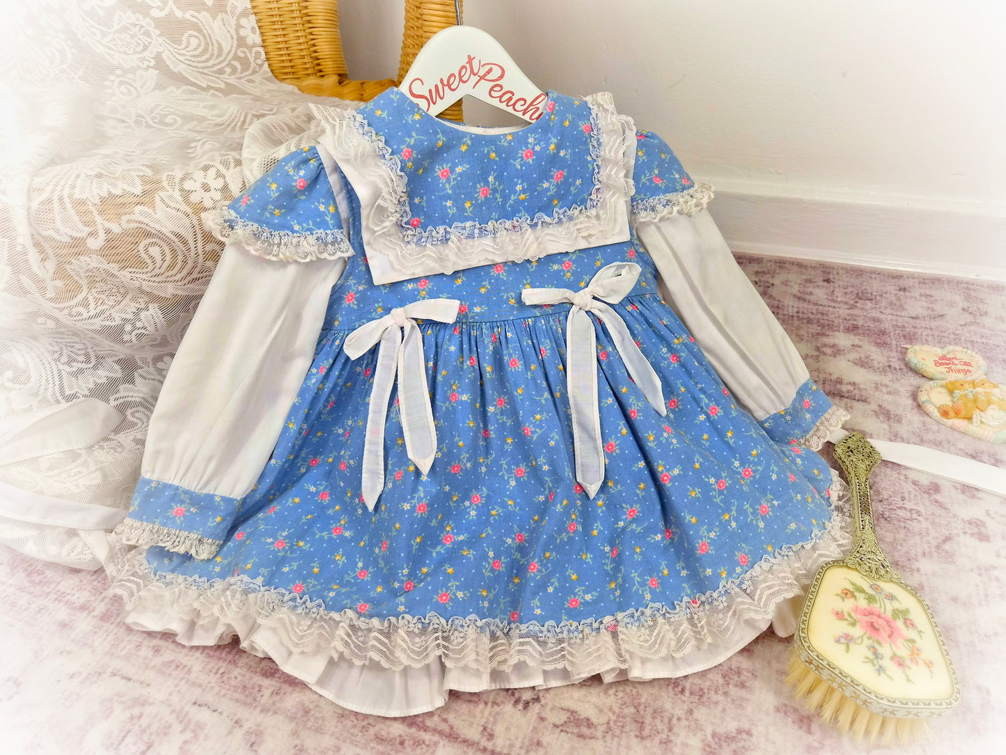 18-24 months. Blue Two-piece vintage dress and pinny with white bow, floral print and lace details