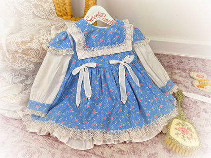 18-24 months. Blue Two-piece vintage dress and pinny with white bow, floral print and lace details