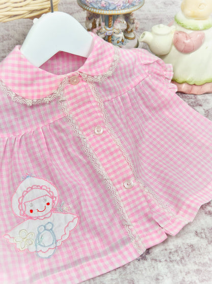 0-3 months. Pink and white lace trimmed, gingham vintage dress with little doll applique