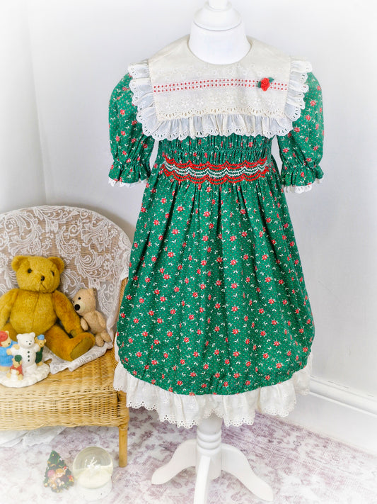 6-7 years. Vintage Polly Flinders smock dress, forest green with cream eyelet bib embroidered with flowers and red embroidered smocking