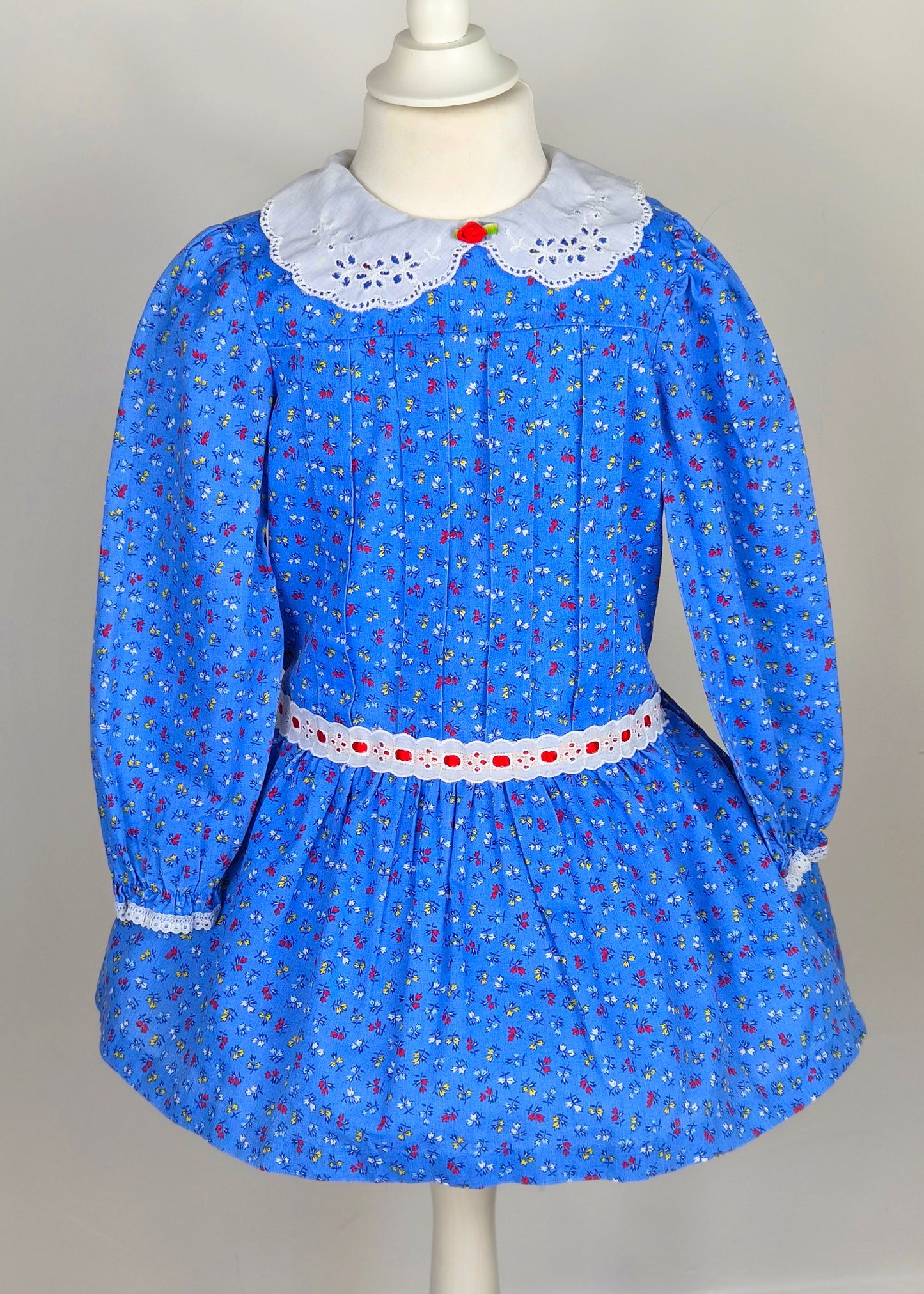 4 years. Blue vintage floral dress from Evy with white eyelet collar, red rosette and ribbon