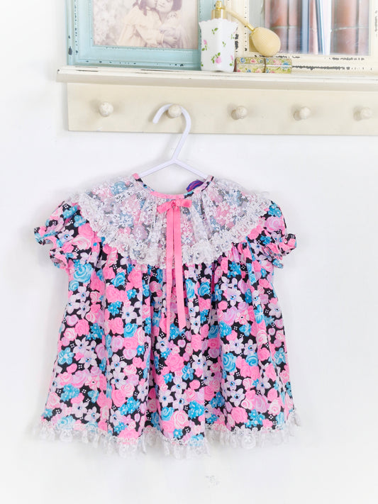 12-18 months. Bright, floral Roanna dress with lace bib and pink ribbon