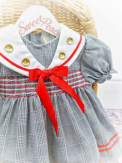 12-18 months. Black and white checked dress with red details and gold buttons