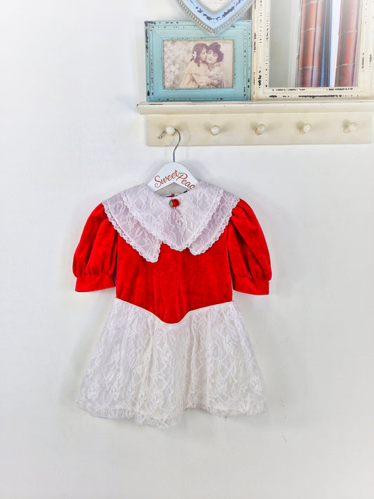 3 years. Red velour dress with white lace, double bib and skirt. Red rosette.
