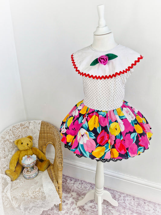 3-4 years. 80s dress, white with polka dot, floral skirt, large bib with rose. Black lace hem.