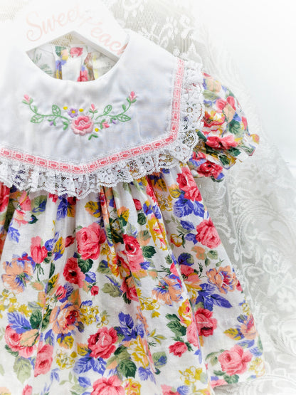9-12 months. Floral dress with white bib embroidered with flowers and finished with lace