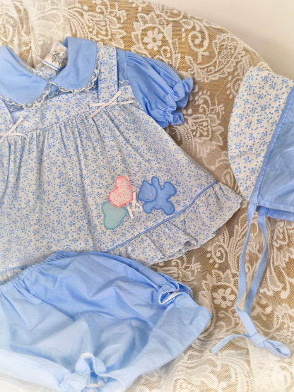 6-12 months. 3 piece vintage Sears set, blue and white floral with teddy applique. Bonnet, dress and bloomers