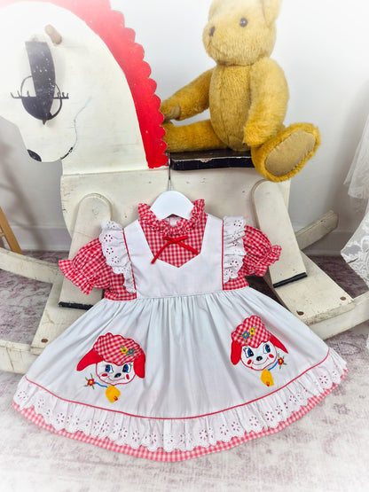 9-12 months. Red and white gingham dress with white mock apron, eyelet details and little sheep appliques