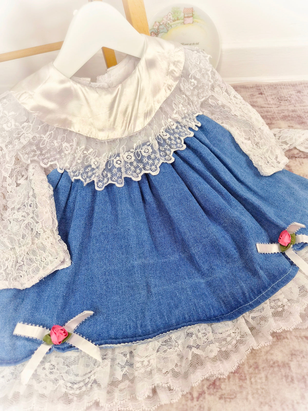 12-18 months. Vintage dress by Shanil, denim with white lace sleeves and hem, satin bib and pink rosettes