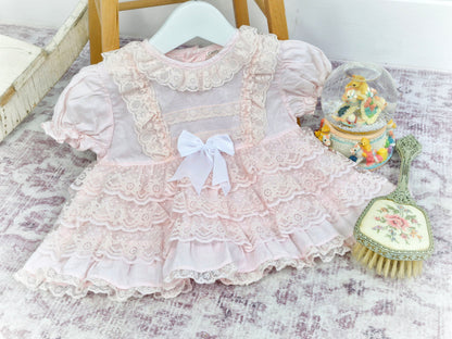 12 months. Pink vintage frilly dress with lace ruffles, puff sleeves and white ribbon