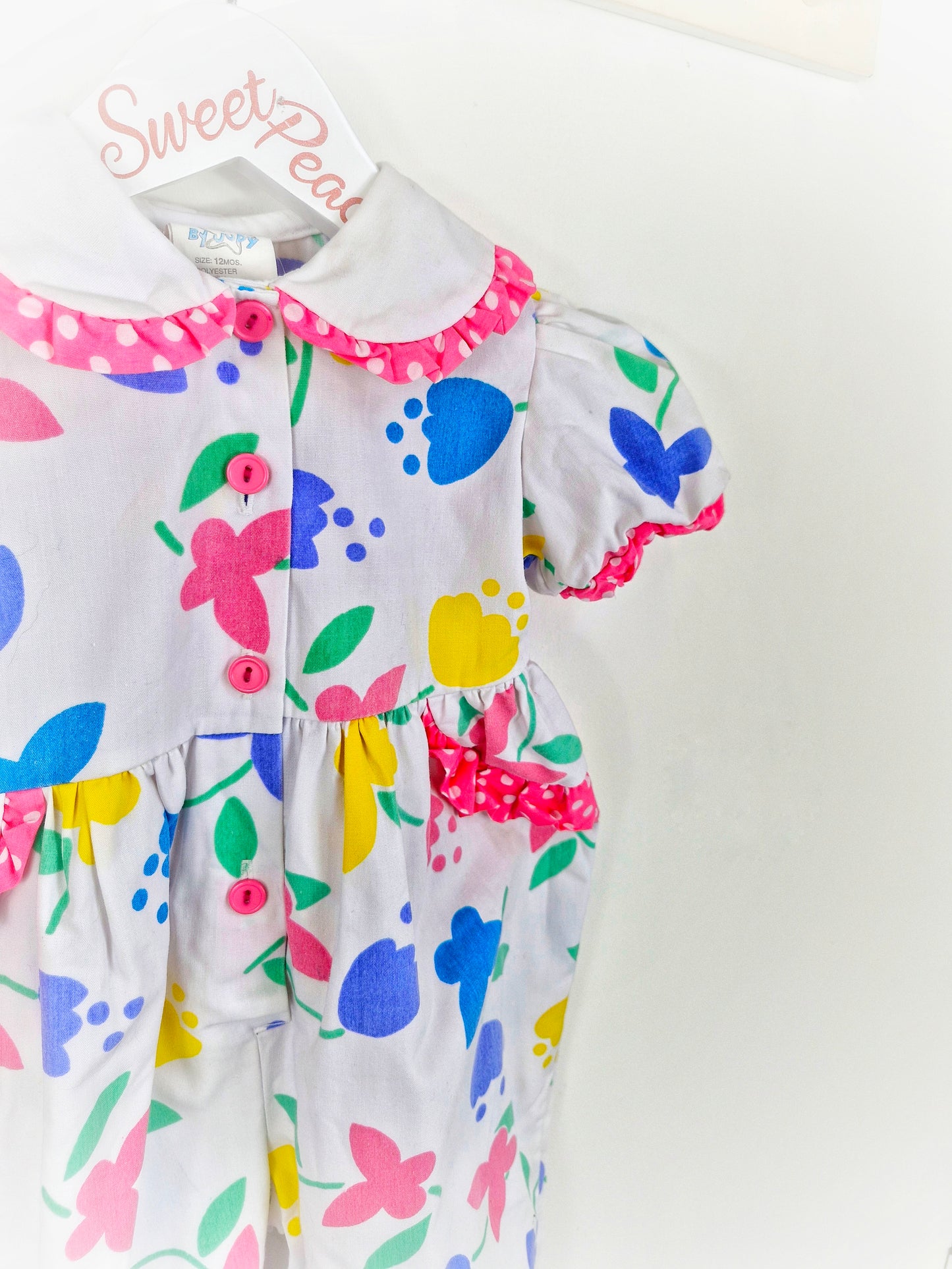 18 months. White romper with bright flowers and butterflies and polka dot trim. From Cuties by Judy