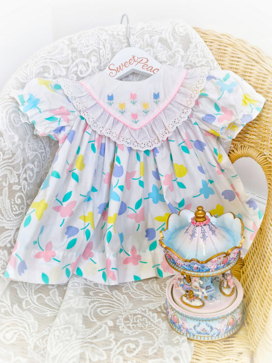 9-12 months. White dress with pastel flowers and butterflies and embroidered bib