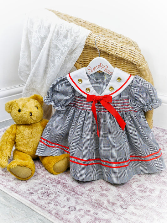 12-18 months. Black and white checked dress with red details and gold buttons