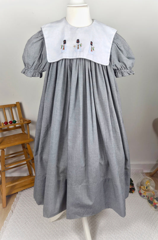 10 years. Black and white gingham, vintage handmade dress by Amanda Kertzembend with large white bib embroidered with snowmen