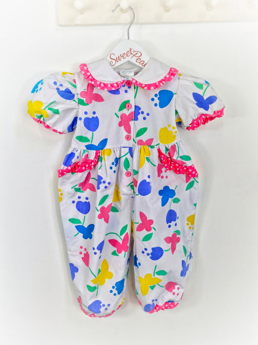 18 months. White romper with bright flowers and butterflies and polka dot trim. From Cuties by Judy