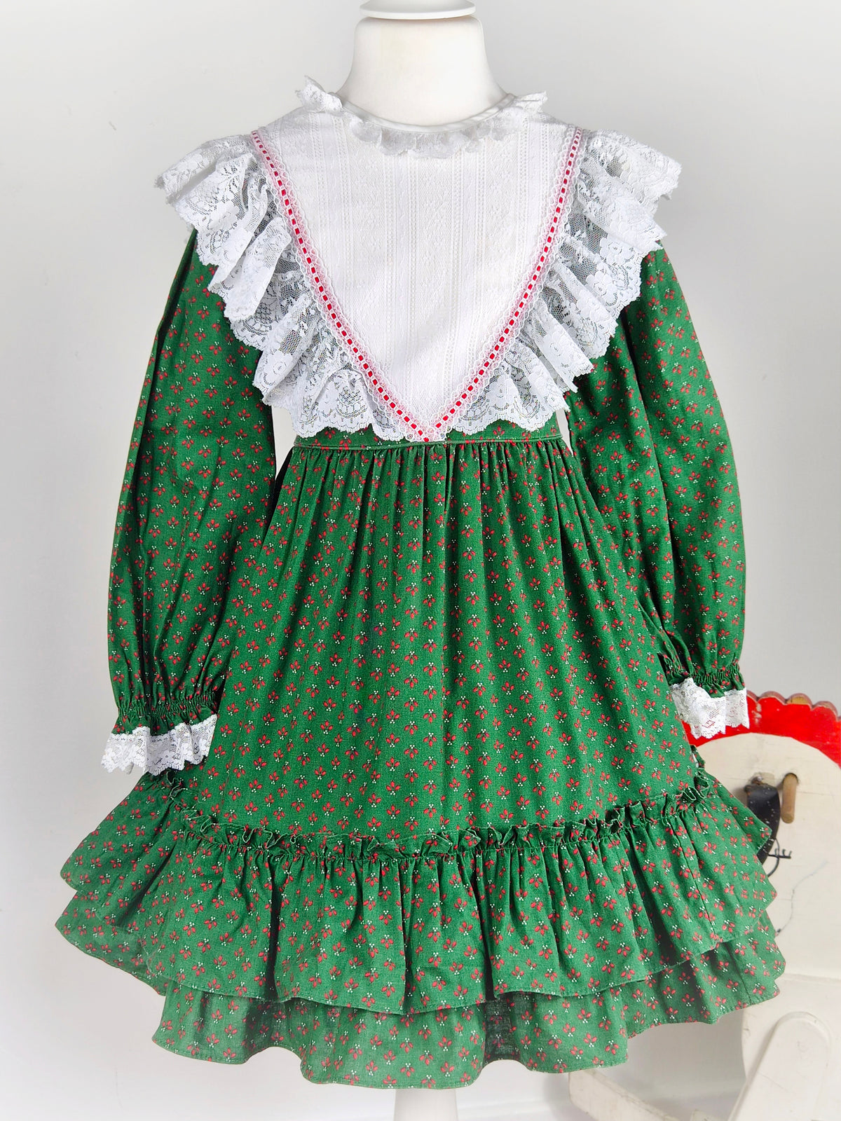 5-6 years. Forest green vintage Bryan prairie dress with red design and white frilly lace bib
